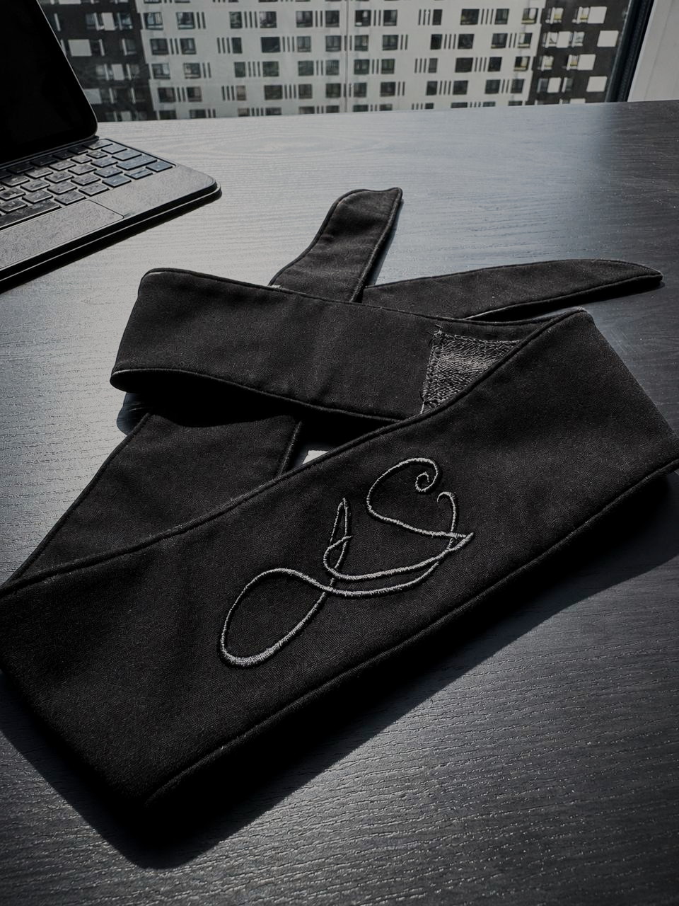 The LS headband folded on a dark desk, monogram facing up